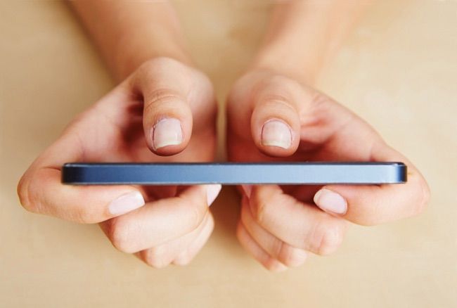 Two thumbs of female hands typing on a smartphone