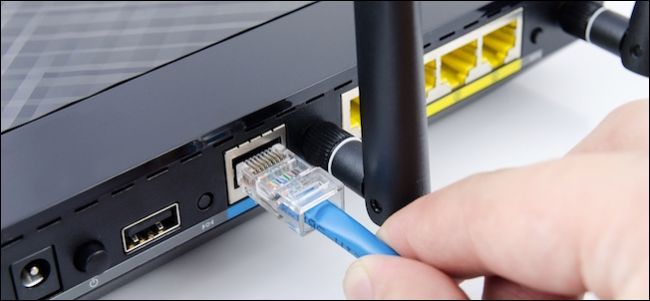 Person plugging an Ethernet cable into a router.
