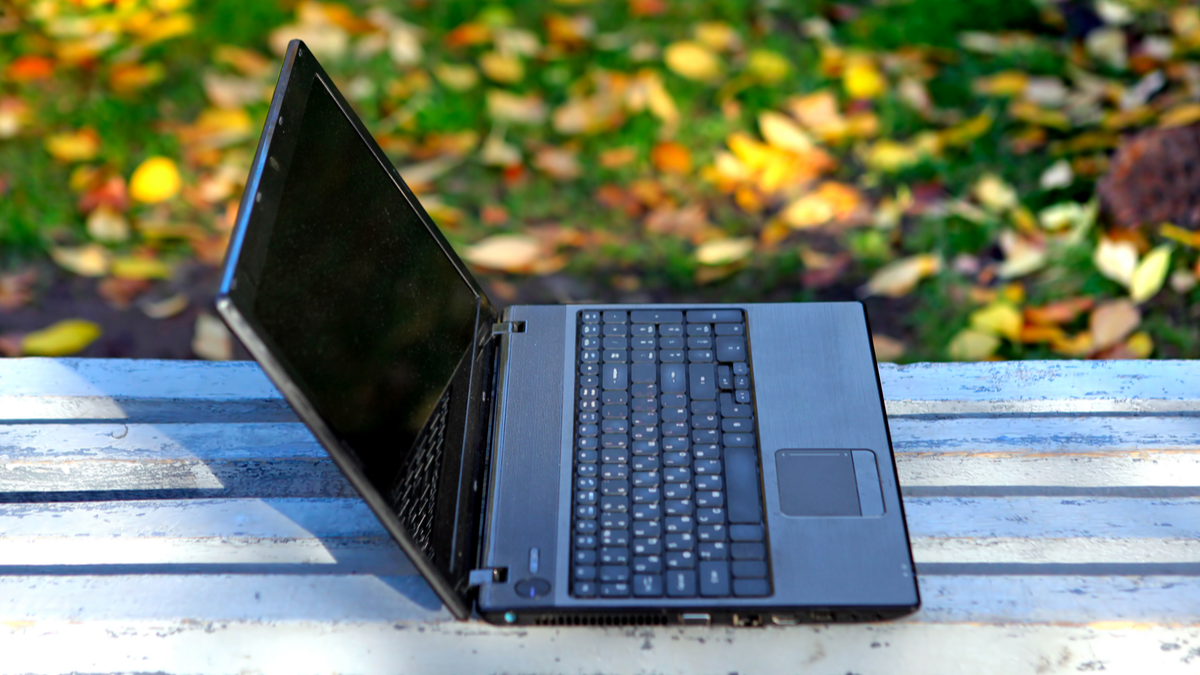 A laptop left open on a park bench.