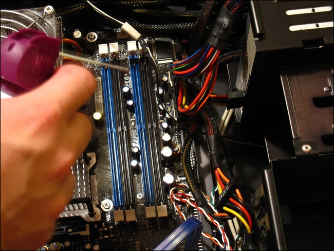 A hand holding a can of air over an open desktop computer tower.