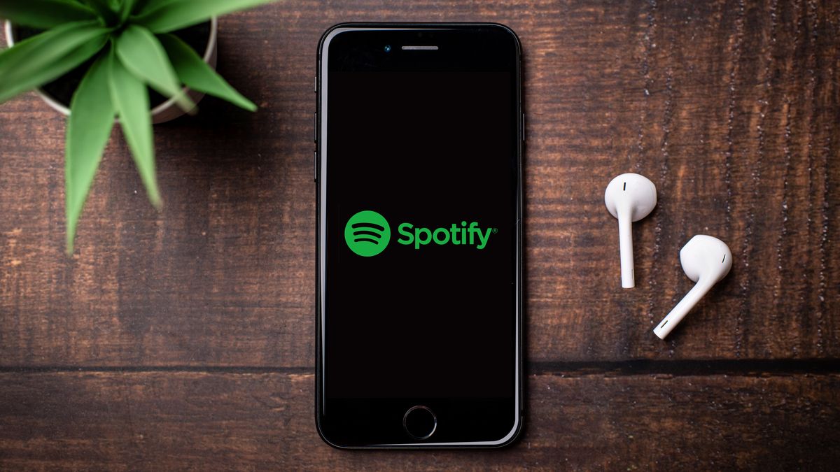Spotify logo on an iPhone next to a pair of AirPods