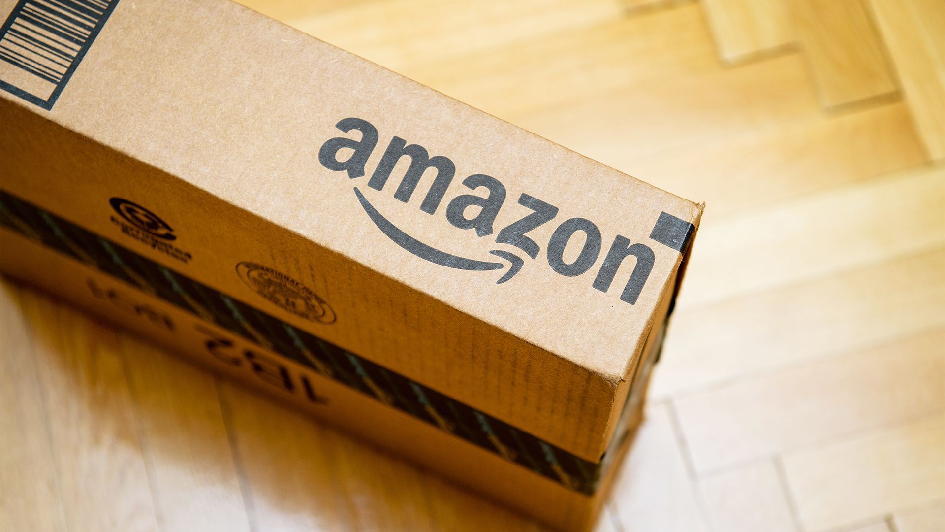 An Amazon box on a wooden floor.