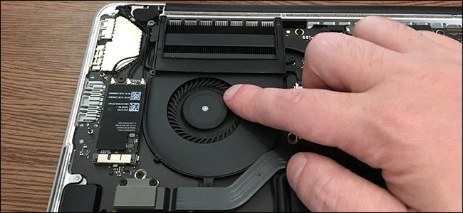 A finger touching the cooling fan inside a MacBook Pro.