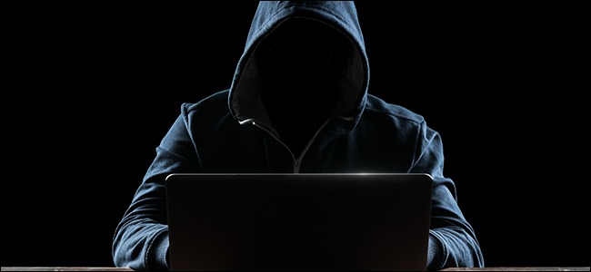 Hooded hacker at laptop computer