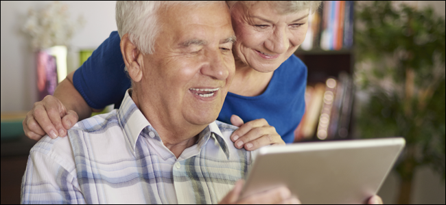 Elderly couple smiling while playing with a tablet