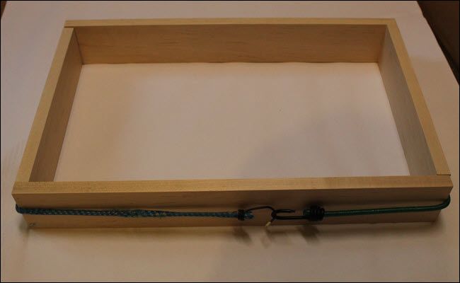Four pieces of wood arranged in a rectangle with a bungee cord pulling them together.
