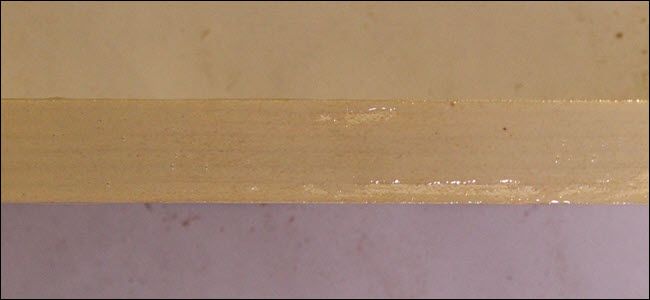 Edge of a board with glue spread across it.