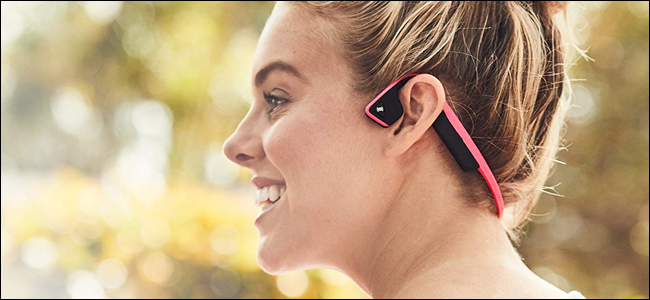 A woman wearing AfterShokz bone conduction headphones. She looks like she's having fun, but she might be telling off a passerby.