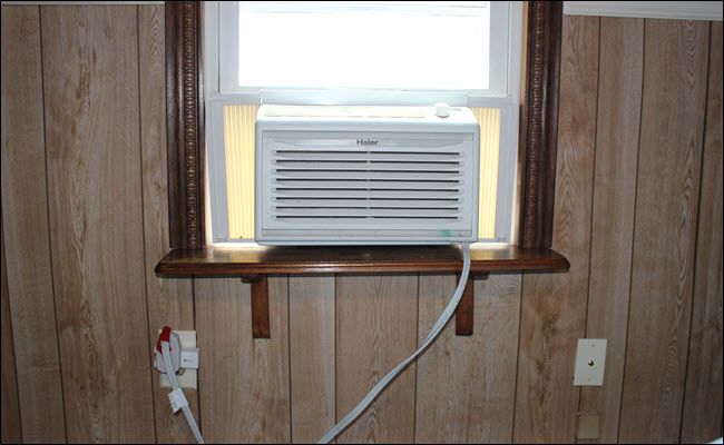 a Window A/C unit connected to a smart plug, which is plugged into an outlet.