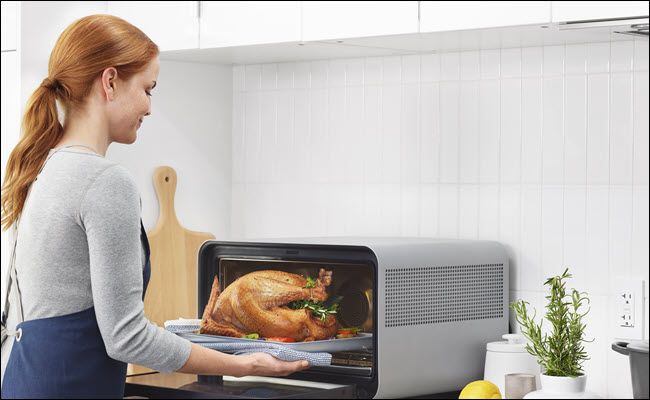 Woman taking a cooking turkey out of a June Smart Oven