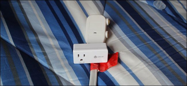An iClever smart plug on top of an A/C units plug, over a blue blanket.
