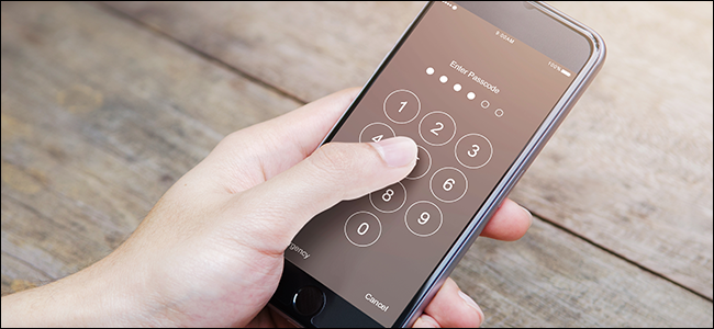A hand typing a passcode into a phone.