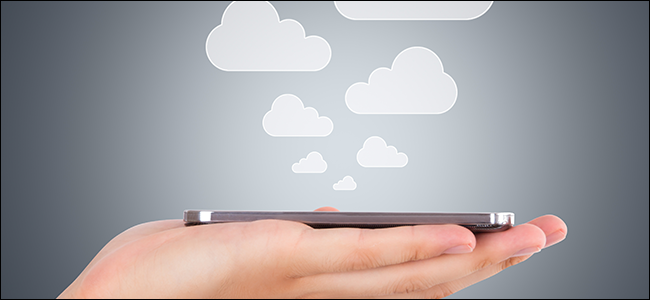 A hand holding a phone as clouds rise out of it, symbolizing files being saved to the cloud.