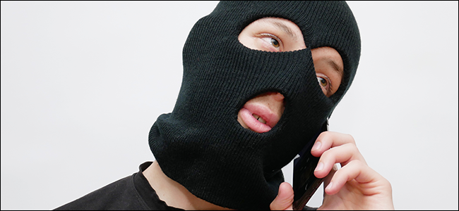 A man in a ski mask talking on a phone.