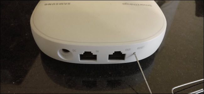 The back of a Samsung Smartthings wireless router with a paperclip sticking in the reset button.