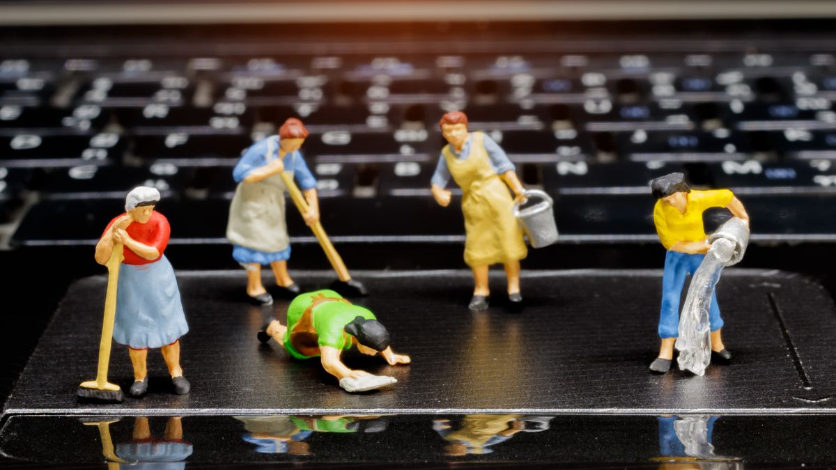 Plastic figures cleaning a laptop