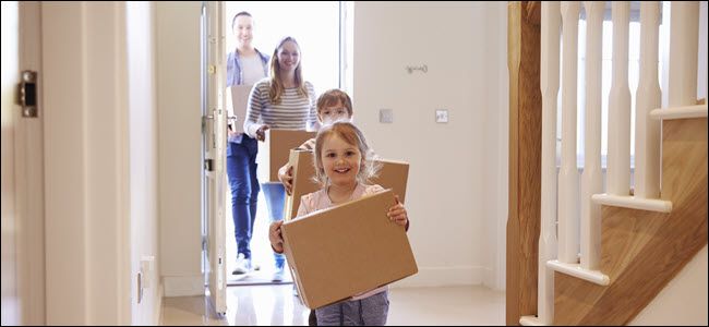 A happy family carrying boxes into a home.