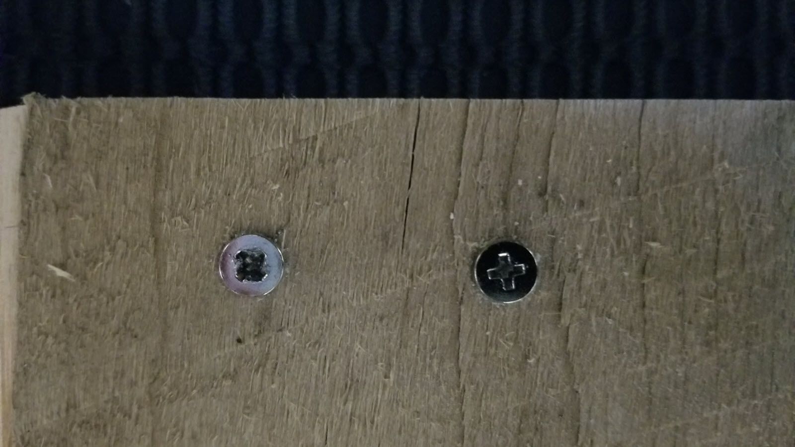 A wood board with two screws in it, the left screw is stripped and the right screw is intact.
