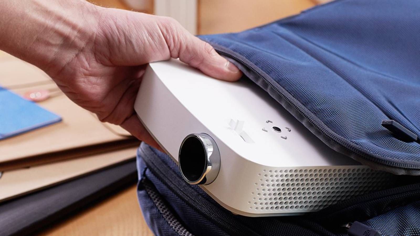 Hand pulling out an LG portable projector out of a bag.