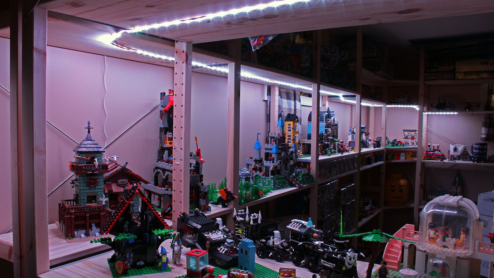 A long strip of white LEDs illuminating a dark room filled with Lego bricks.
