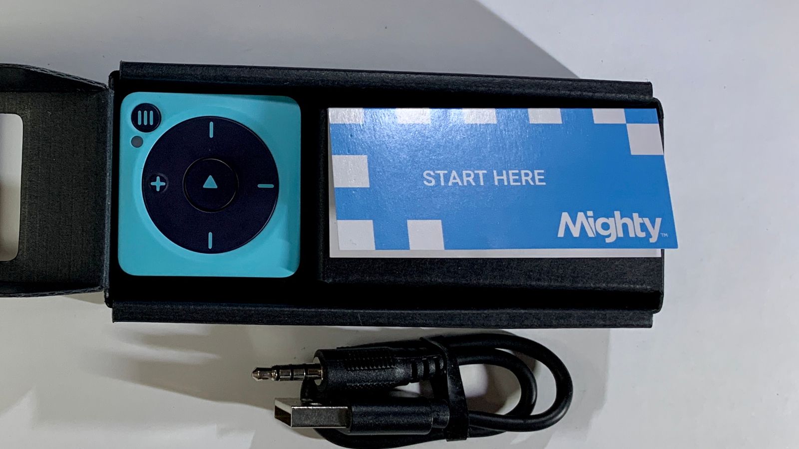 The Mighty Vibe player in its box with the &quot;Start Here&quot; booklet next to the charging cable