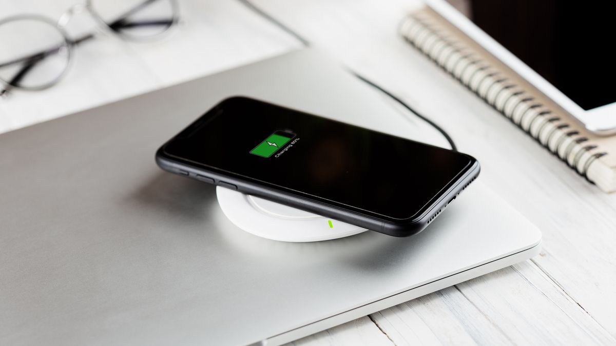 An Apple iPhone sitting on a wireless QI charger