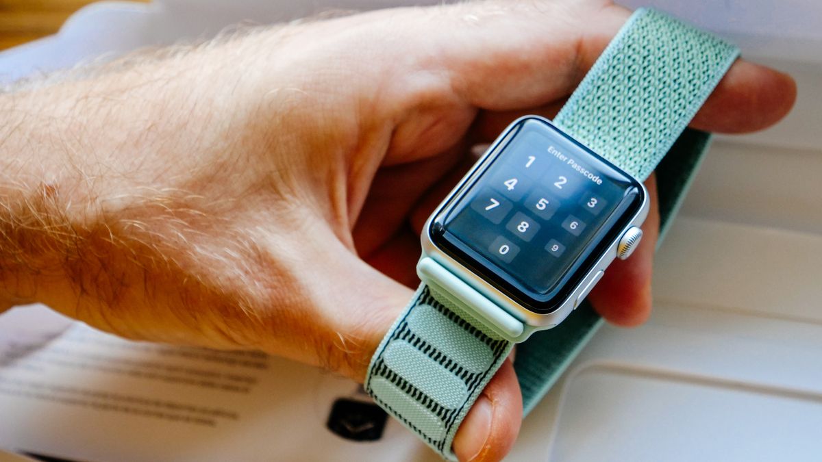Person holding an Apple Watch by its band