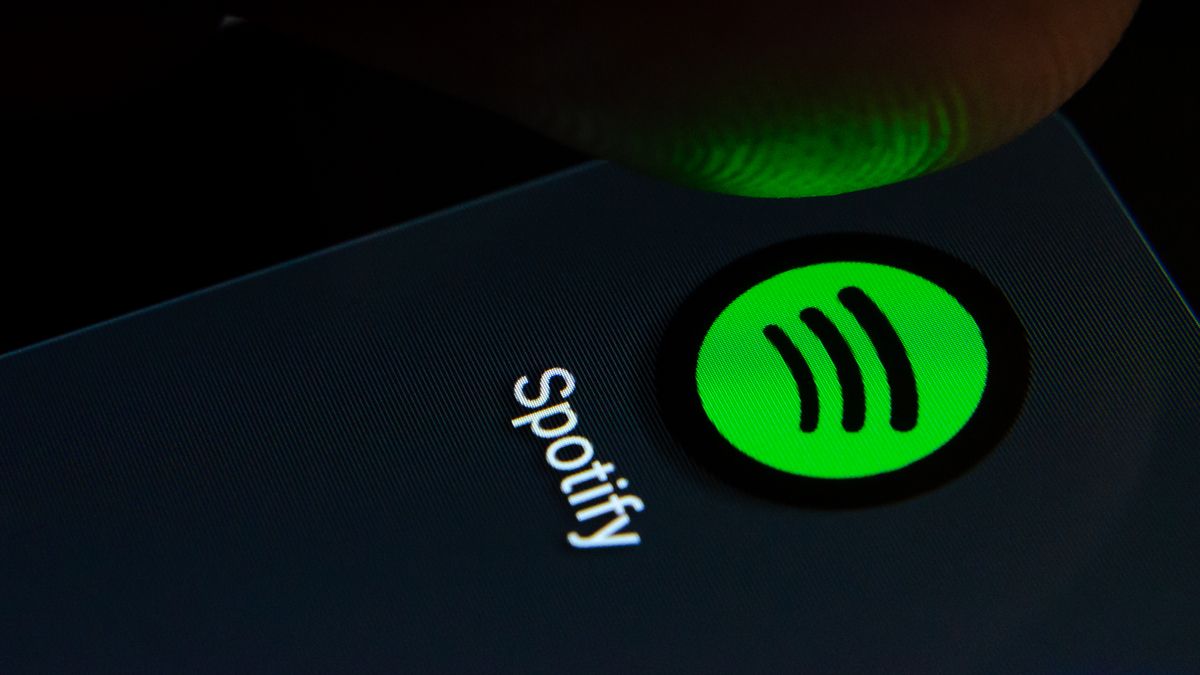 Person tapping the Spotify app logo on a smartphone