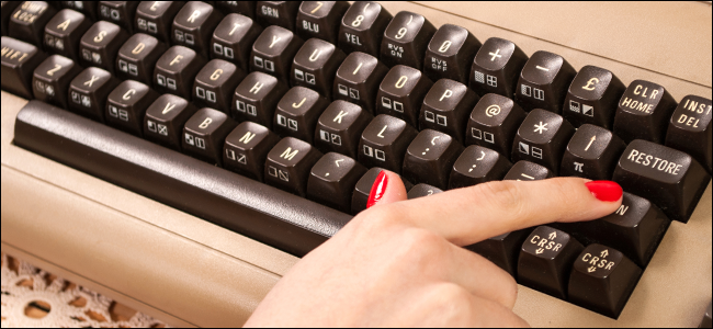 A woman typing on an old keyboard.
