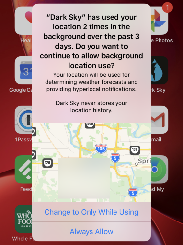 A background location use warning for Dark Sky on an iPhone's home screen.