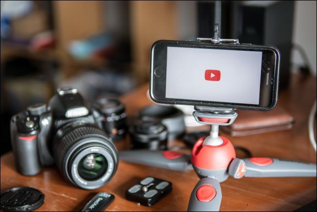 A camera sitting on a table next to a smartphone that's mounted on a table tripod.