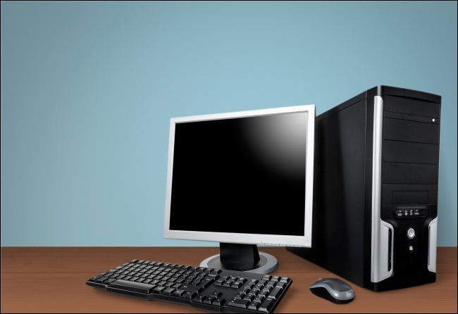 A desktop PC case, monitor, keyboard, and mouse on a table.