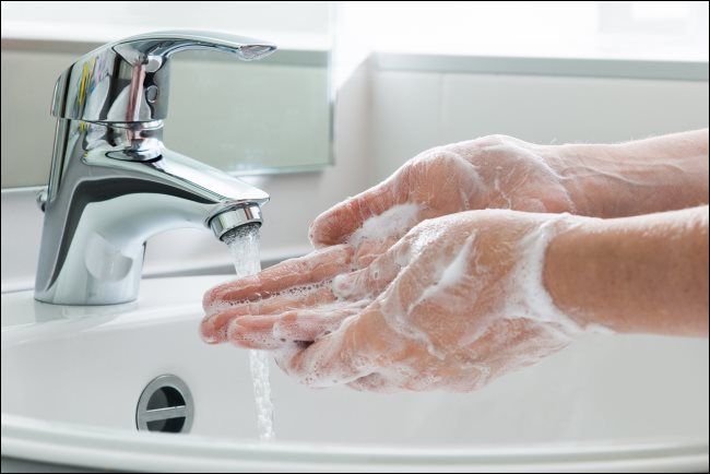 Washing hands with soap under a water tap.