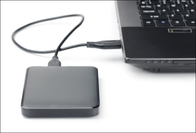 An external hard drive connected to a laptop via a USB cable.