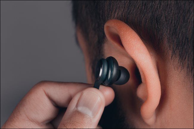 A man inserting an earbud into his ear.