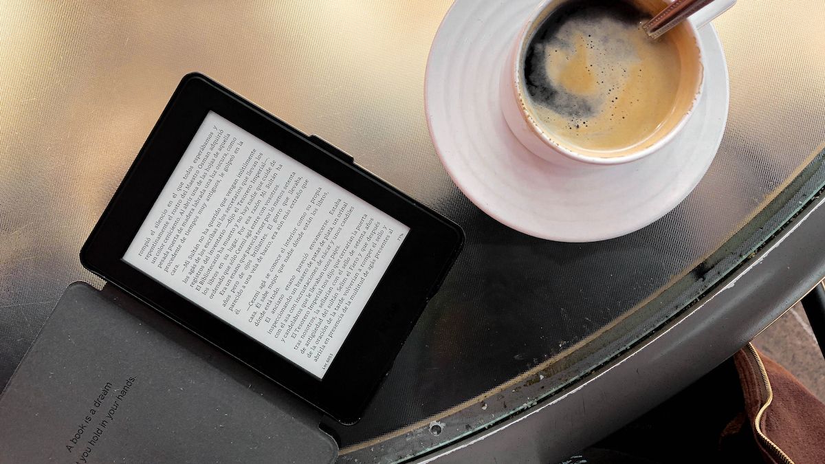 Kindle laying on a tablet next to a cup of coffee