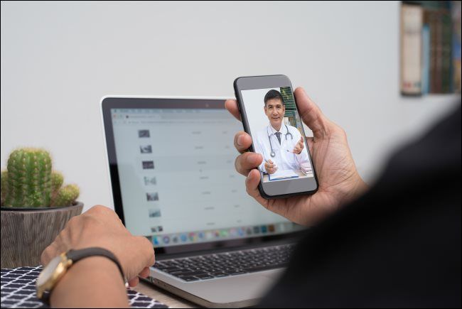 A man communicating with a doctor via video chat on a smartphone.