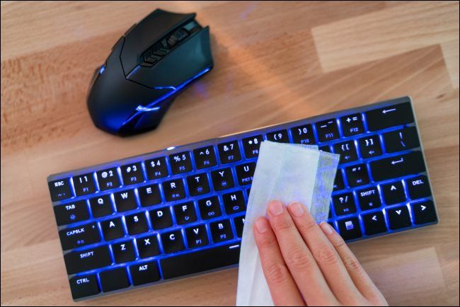 A hand wiping a detached keyboard.