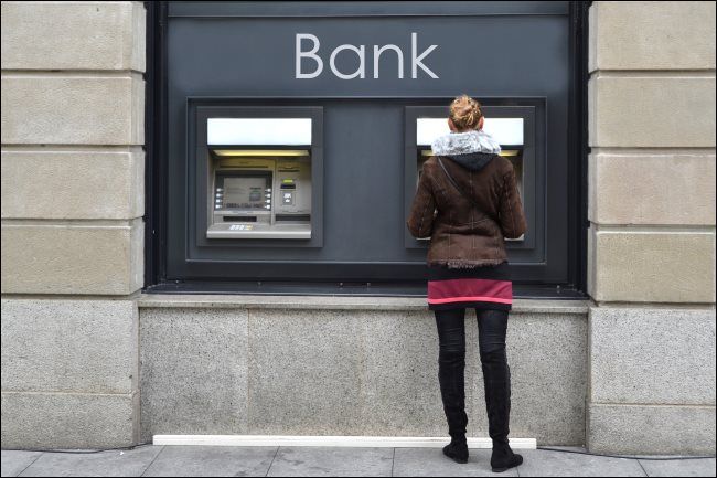 A woman using an outdoor ATM.