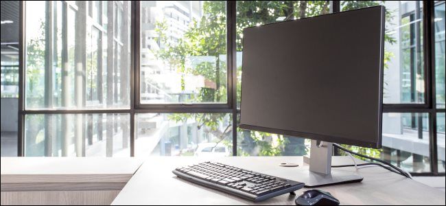 A PC monitor, keyboard, and mouse on an office desk.
