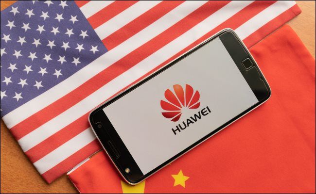 A Huawei phone between a USA and Chinese flag.