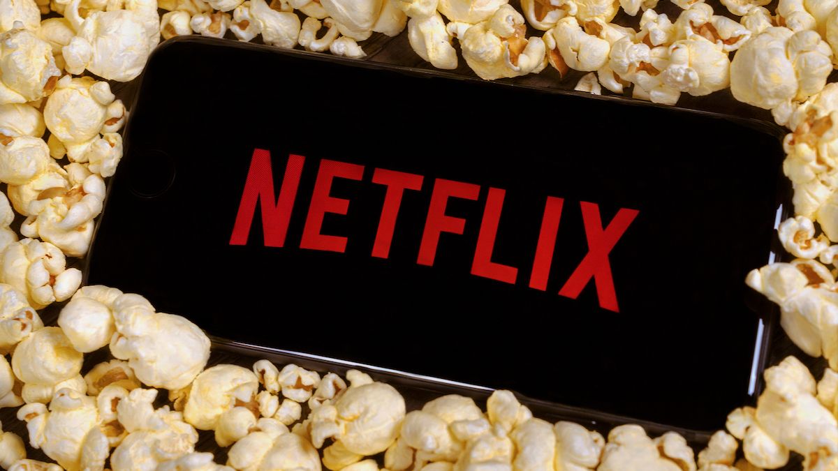 The Netflix logo on a smartphone sitting on a pile of popcorn