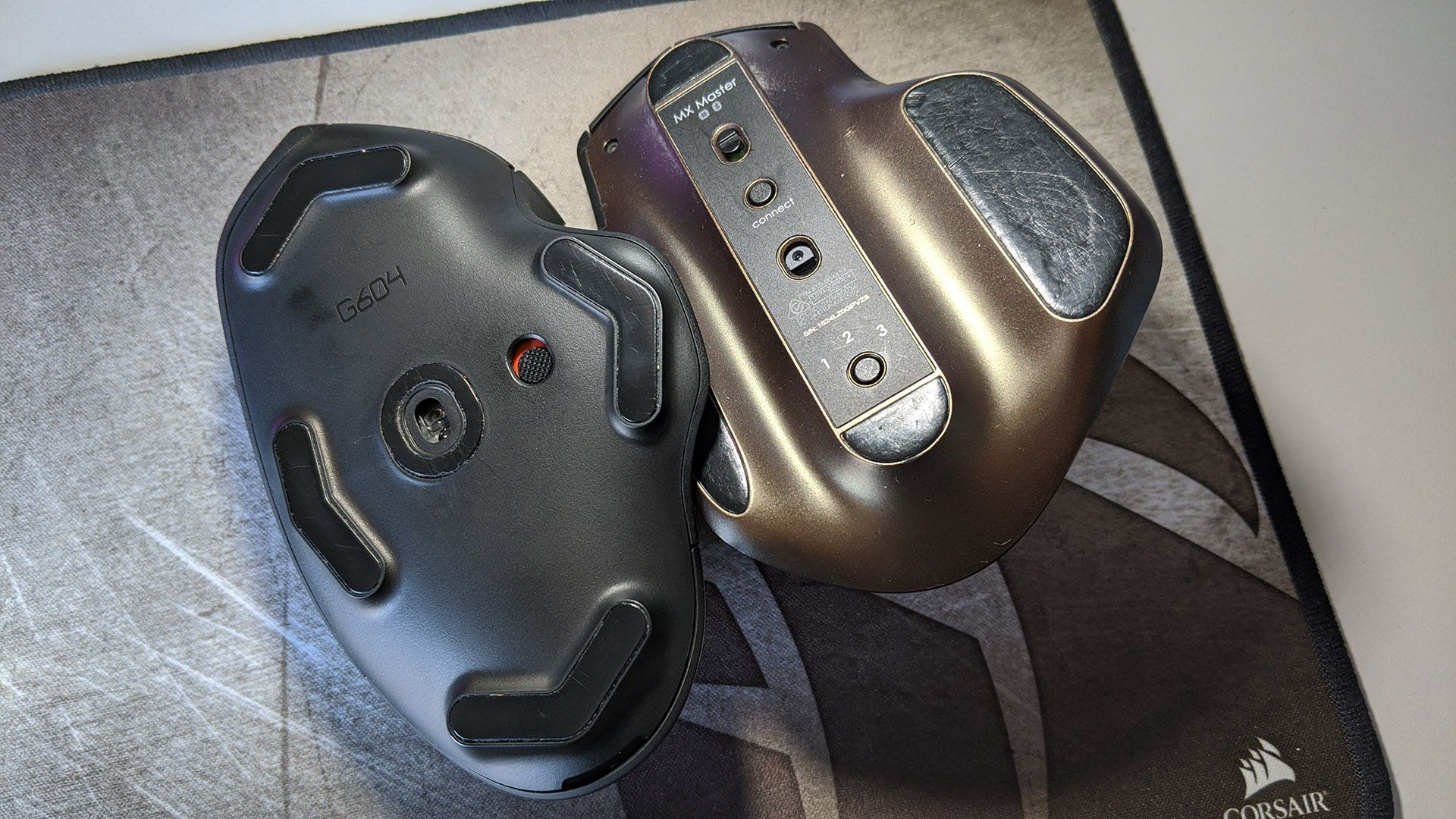 Two computer mice, upside down, with one worn and one clean.