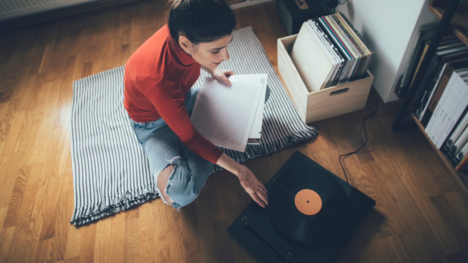 Young audiophile playing vinyl record on turntable in her home.