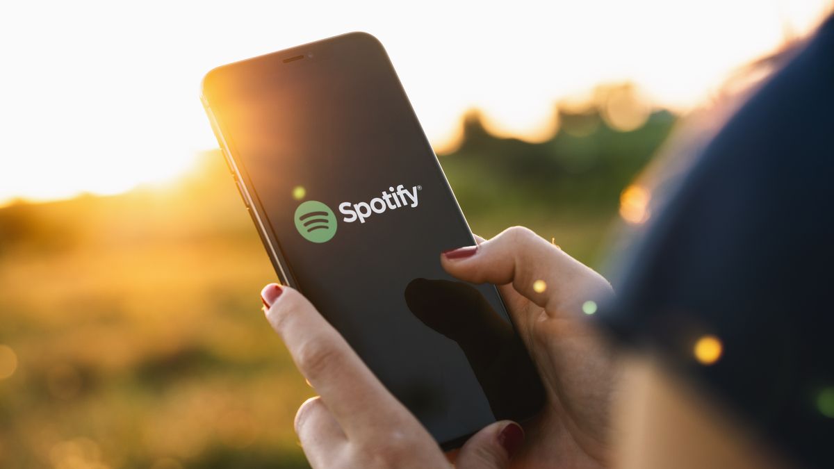 Person using a smartphone with the Spotify logo on it