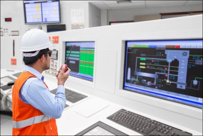An electrical engineer in front of computers in the control room of a thermal power plant.