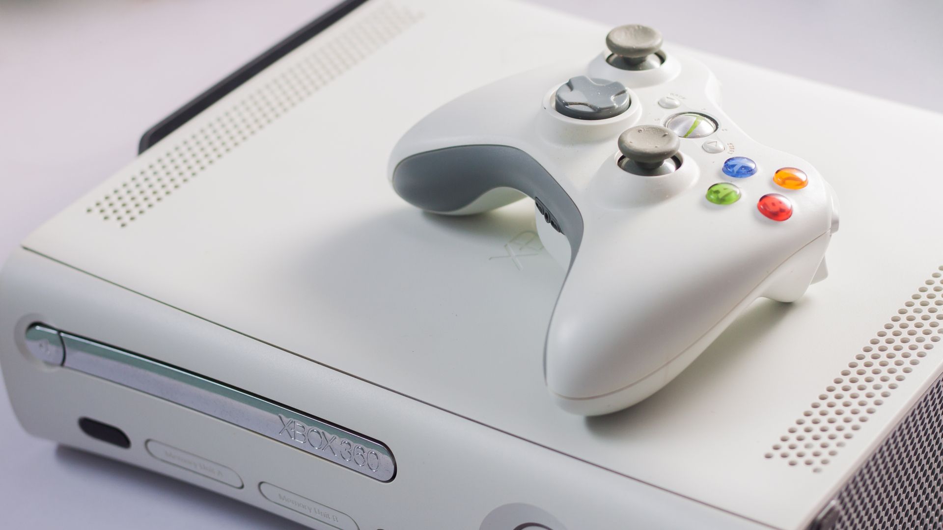A white Xbox 360 on a table with a controller.