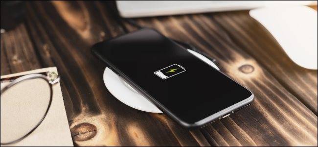 A smartphone charging on a wireless charging pad.