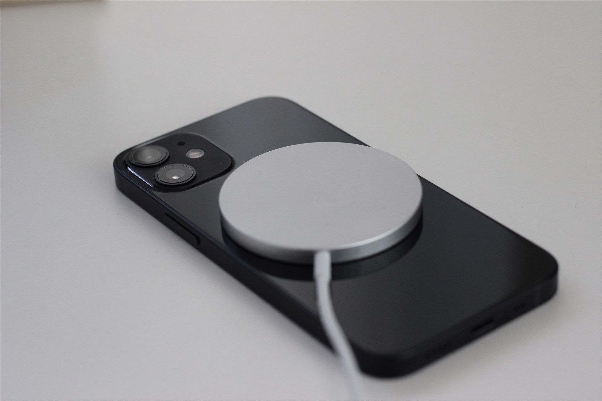 The black iPhone 12 Mini with the MagSafe wireless charger connected