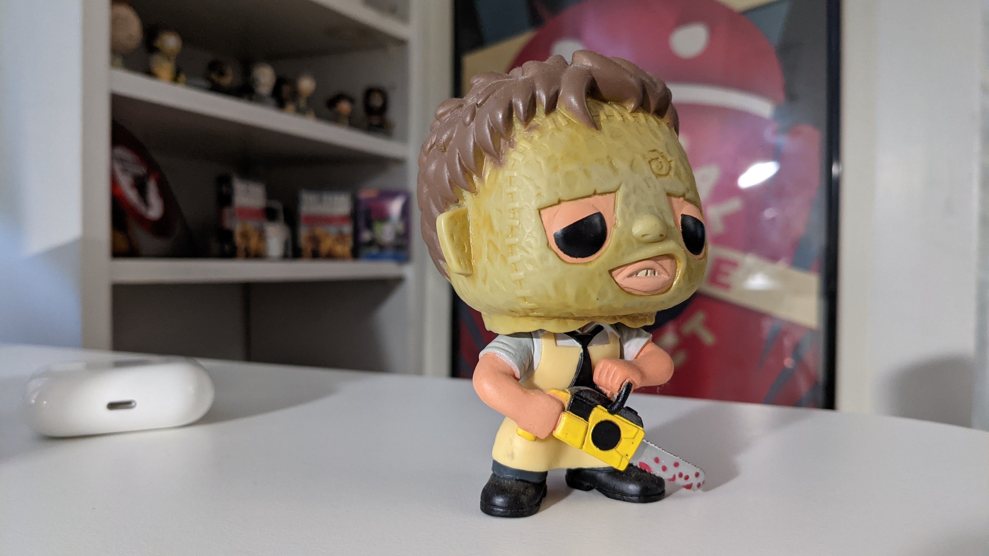 A sample picture from the Pixel 5: A Leatherface collectible on a white desk; AirPods and other memorabilia in the background